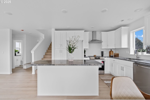 kitchen featuring sink, white cabinetry, stainless steel appliances, a center island, and wall chimney exhaust hood