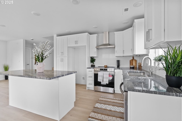 kitchen with a kitchen island, white cabinetry, sink, wall chimney range hood, and electric stove