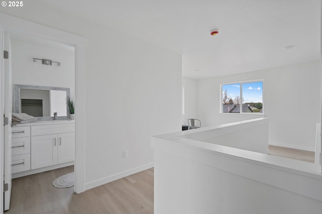 bar featuring sink, light hardwood / wood-style floors, and white cabinets