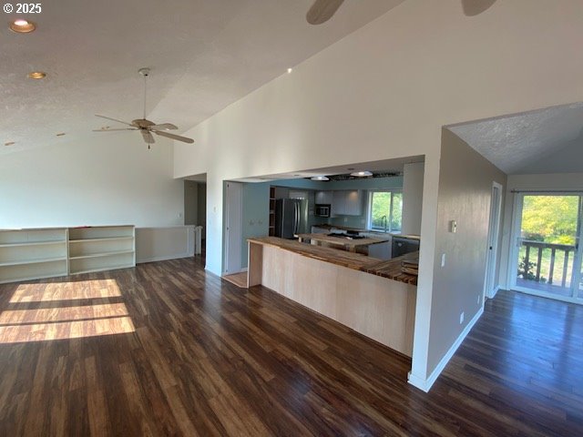 kitchen with ceiling fan, dark wood-style floors, freestanding refrigerator, baseboards, and high vaulted ceiling