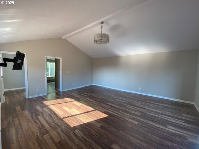 spare room featuring dark wood-style floors, baseboards, vaulted ceiling, and a chandelier