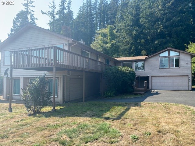 view of front facade with a garage, a front yard, driveway, and a deck