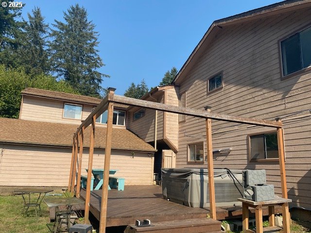 back of house with a hot tub and a deck
