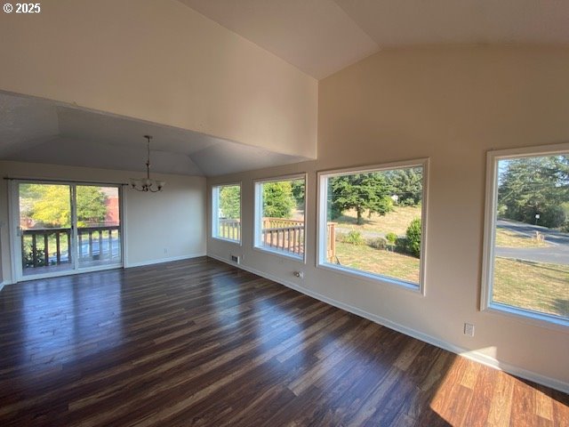 unfurnished room featuring vaulted ceiling, a chandelier, dark wood-style floors, and baseboards