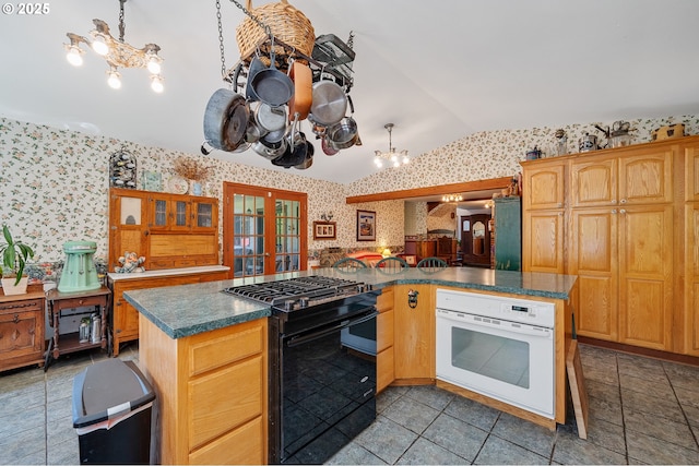 kitchen with french doors, gas stove, a notable chandelier, wallpapered walls, and oven
