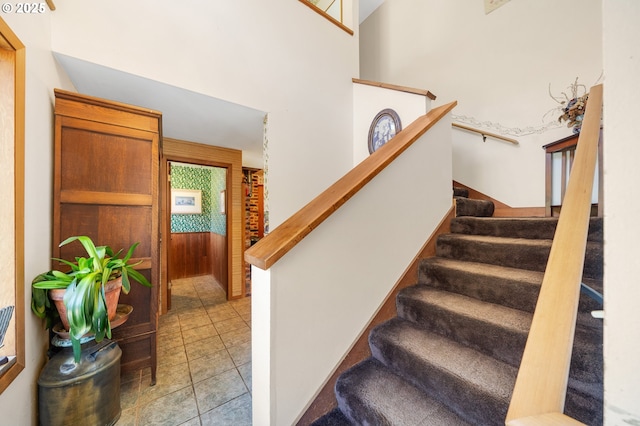 staircase with tile patterned flooring and a towering ceiling
