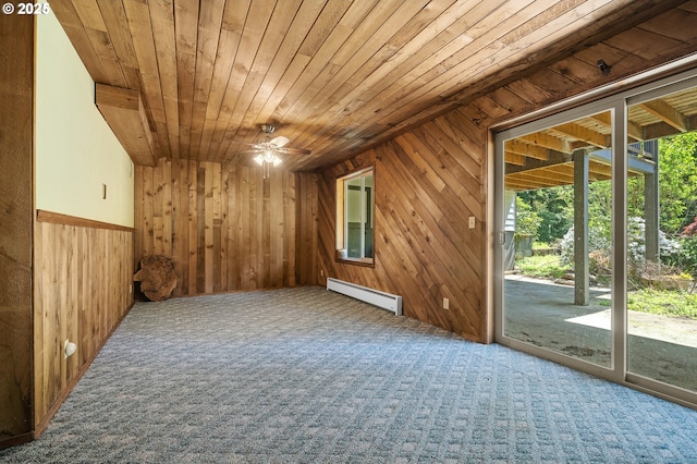 carpeted spare room with wooden walls, wood ceiling, a baseboard radiator, and a ceiling fan
