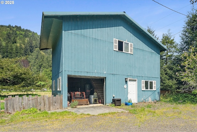 view of side of property featuring central AC, fence, and a garage