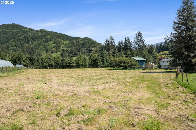 view of yard featuring a mountain view, fence, and a forest view