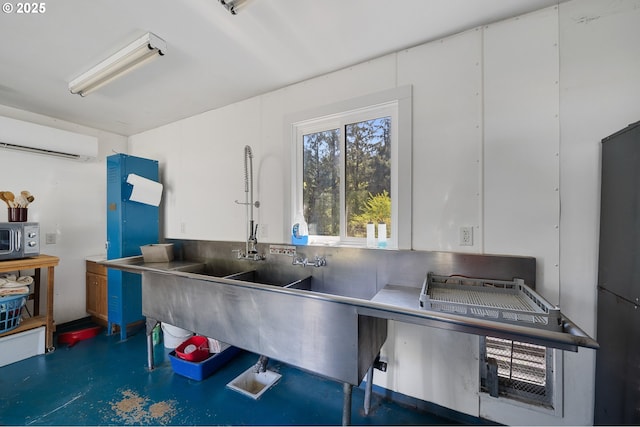kitchen with finished concrete flooring, stainless steel microwave, an AC wall unit, and stainless steel countertops