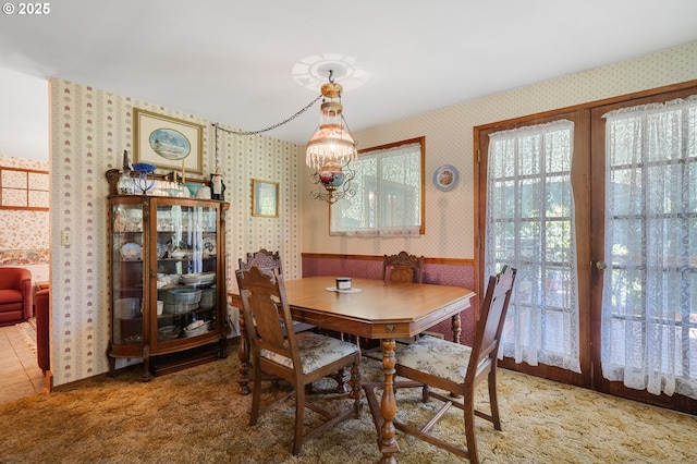 dining space with light carpet, wallpapered walls, and a chandelier