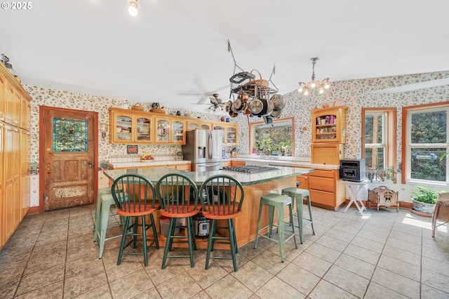 kitchen with a healthy amount of sunlight, a center island, stainless steel appliances, and wallpapered walls