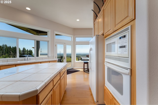 20700 SE Cherry Blossom Ln, Amity, OR 97101 - kitchen featuring white appliances, tile countertops, light wood-style flooring, light brown cabinets, and healthy amount of natural light