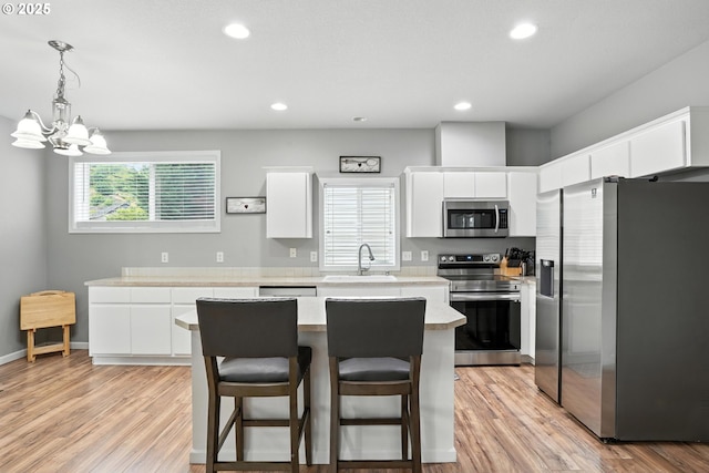 2137 N Q St, Washougal, WA 98671 - kitchen featuring appliances with stainless steel finishes, light countertops, a center island, white cabinets, and light wood-type flooring