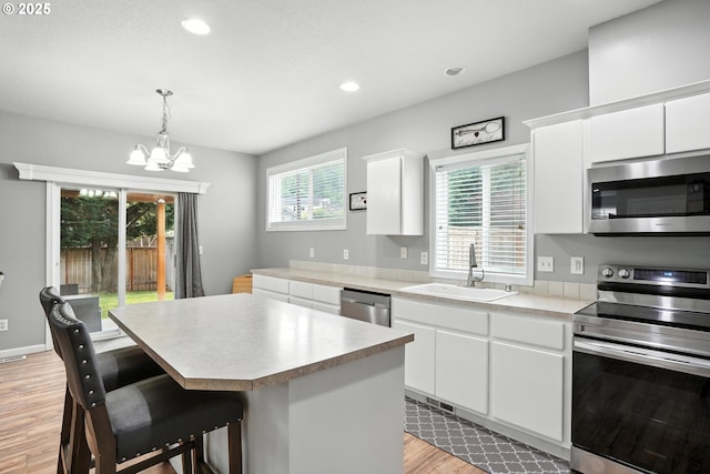 2137 N Q St, Washougal, WA 98671 - kitchen with appliances with stainless steel finishes, light wood finished floors, a chandelier, light countertops, and a center island