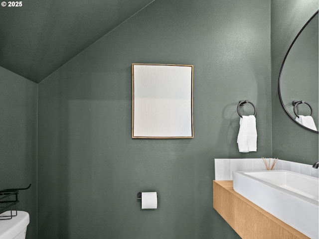 bathroom featuring lofted ceiling, sink, and toilet