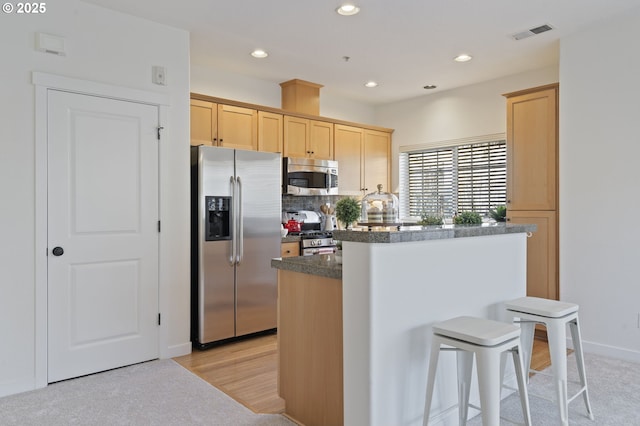 kitchen with a kitchen island, appliances with stainless steel finishes, and light brown cabinets