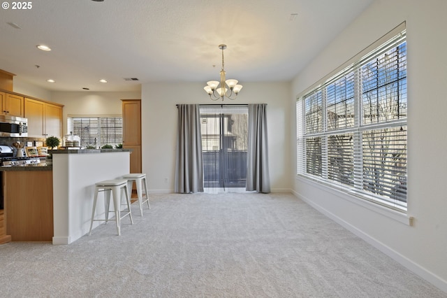 kitchen with decorative light fixtures, light colored carpet, a breakfast bar, and a chandelier