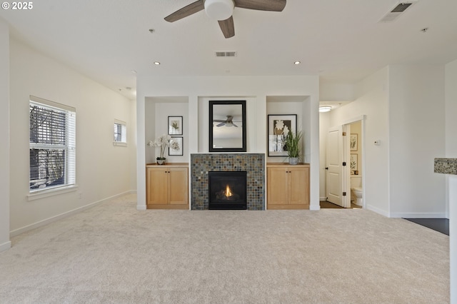 unfurnished living room with ceiling fan, light colored carpet, and a fireplace