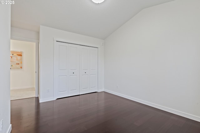 unfurnished bedroom featuring a closet, vaulted ceiling, and dark hardwood / wood-style floors