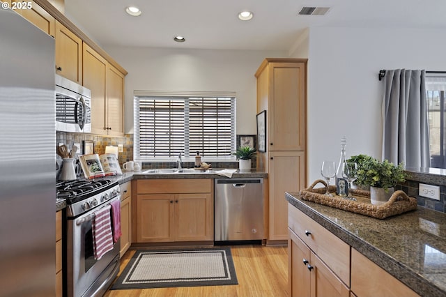 kitchen with sink, appliances with stainless steel finishes, light hardwood / wood-style floors, light brown cabinetry, and decorative backsplash