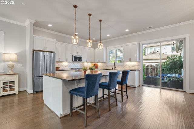12339 SW Waterford Loop, Wilsonville, OR 97070 - kitchen with appliances with stainless steel finishes, a center island, white cabinetry, a kitchen bar, and tasteful backsplash