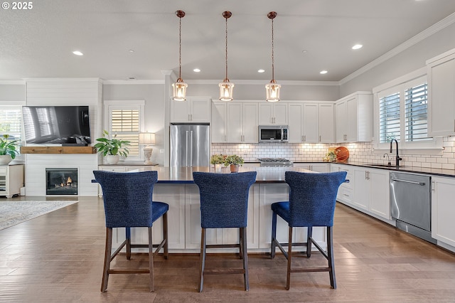 12339 SW Waterford Loop, Wilsonville, OR 97070 - kitchen with appliances with stainless steel finishes, a sink, a kitchen island, a breakfast bar area, and crown molding
