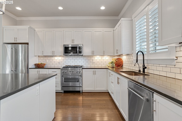 12339 SW Waterford Loop, Wilsonville, OR 97070 - kitchen featuring premium appliances, a sink, white cabinets, ornamental molding, and dark wood-style floors