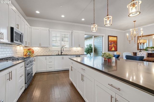 12339 SW Waterford Loop, Wilsonville, OR 97070 - kitchen with appliances with stainless steel finishes, a sink, ornamental molding, dark countertops, and tasteful backsplash