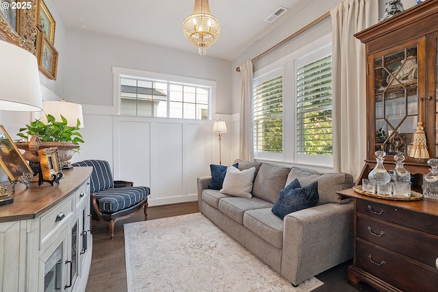 12339 SW Waterford Loop, Wilsonville, OR 97070 - living room featuring wainscoting, a chandelier, a decorative wall, and dark wood-type flooring