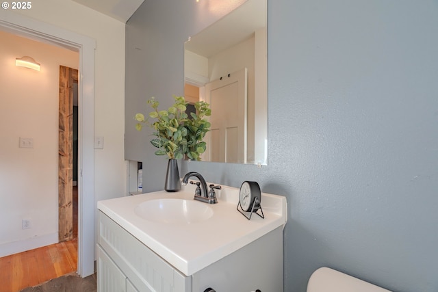 bathroom featuring toilet, vanity, and hardwood / wood-style floors