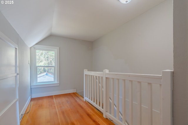 additional living space with hardwood / wood-style floors and lofted ceiling