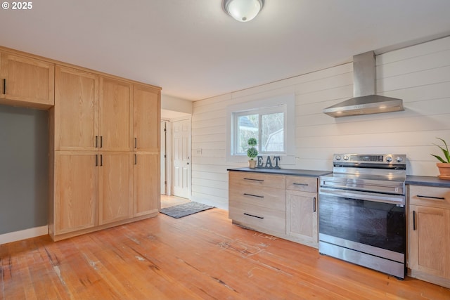 kitchen featuring wall chimney exhaust hood, light hardwood / wood-style flooring, wooden walls, electric range, and light brown cabinets