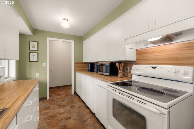 kitchen featuring electric range, stainless steel microwave, stone finish floors, and white cabinetry