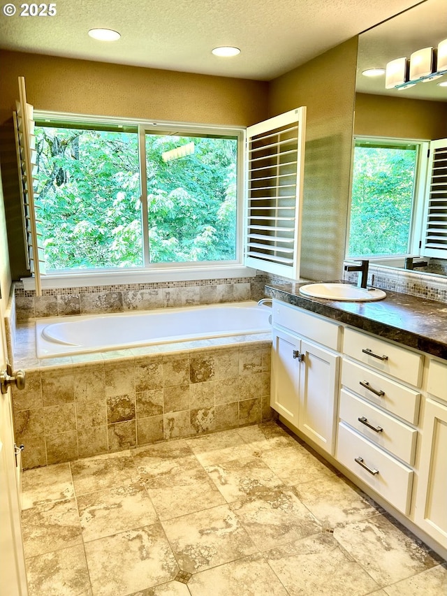 2107 NW Village Cir, Portland, OR 97229 - bathroom with healthy amount of natural light, a bath, vanity, a textured ceiling, and stone finish flooring