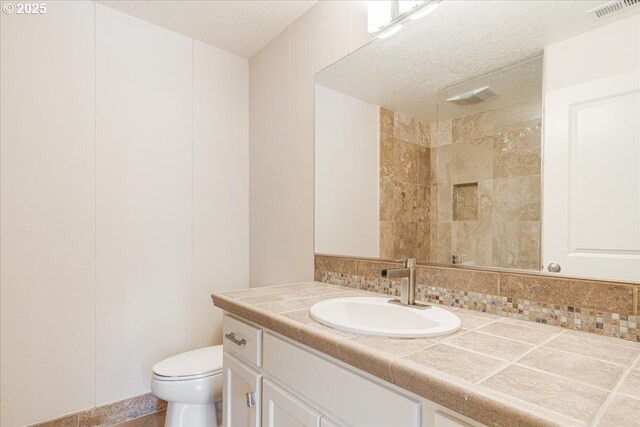 2107 NW Village Cir, Portland, OR 97229 - bathroom featuring vanity, toilet, a textured ceiling, tiled shower, and tasteful backsplash
