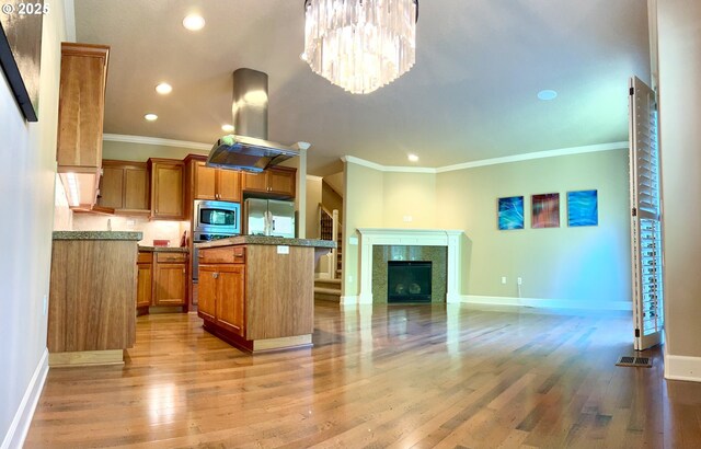 2107 NW Village Cir, Portland, OR 97229 - kitchen featuring appliances with stainless steel finishes, crown molding, brown cabinets, baseboards, and a kitchen island
