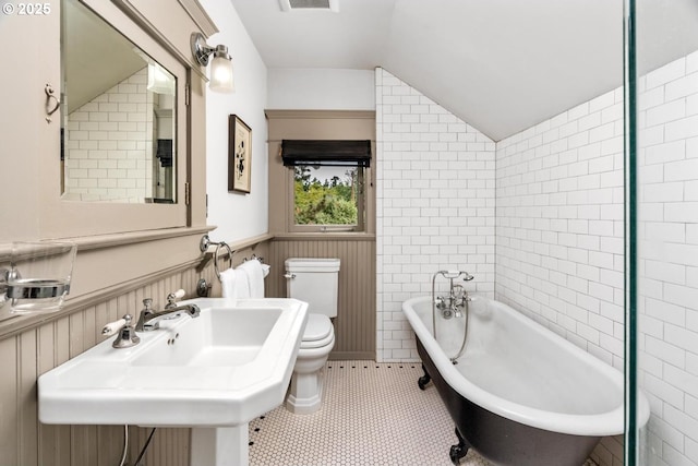 2517 NE 21st Ave, Portland, OR 97212 - bathroom featuring a soaking tub, vaulted ceiling, wainscoting, and tile patterned floors