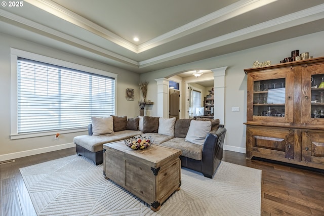 living area featuring decorative columns, baseboards, arched walkways, dark wood finished floors, and crown molding