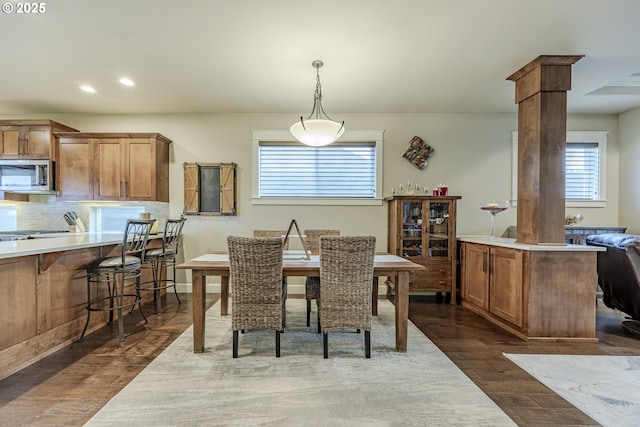 dining area with dark wood-style floors, recessed lighting, and ornate columns