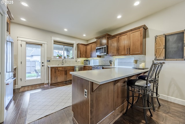 kitchen featuring a peninsula, brown cabinetry, stainless steel appliances, and light countertops