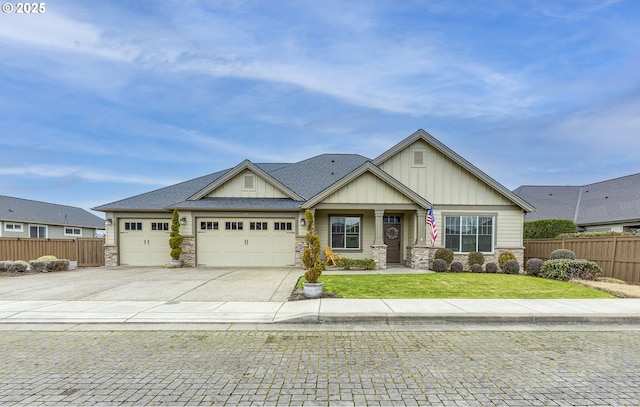 craftsman-style house featuring board and batten siding, fence, a garage, stone siding, and driveway