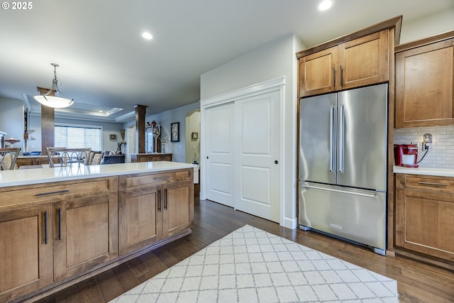 kitchen featuring arched walkways, high end fridge, light countertops, and decorative light fixtures