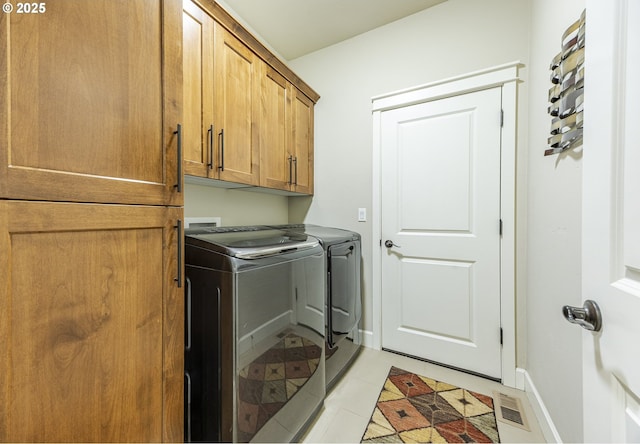 clothes washing area featuring cabinet space, visible vents, baseboards, washer and dryer, and light tile patterned flooring