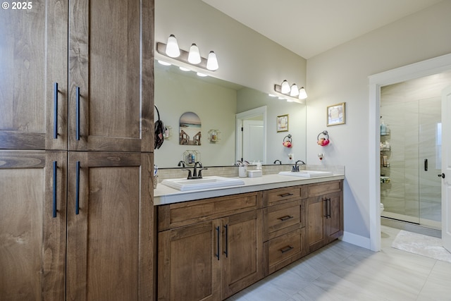 bathroom with double vanity, a stall shower, baseboards, and a sink