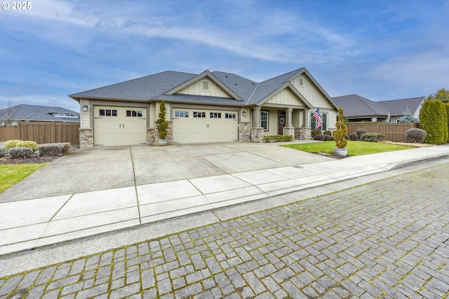 craftsman-style home featuring concrete driveway, stone siding, an attached garage, fence, and board and batten siding