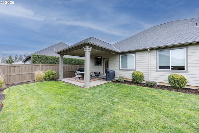 rear view of property featuring a patio area, a shingled roof, fence, and a yard