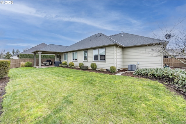 back of property featuring a yard, a patio, a shingled roof, central AC unit, and a fenced backyard