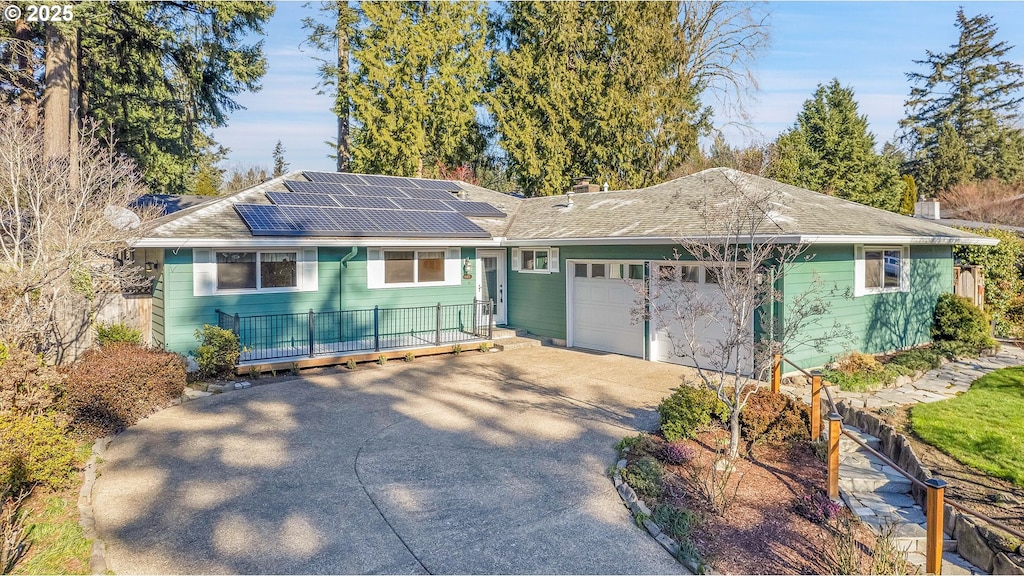 ranch-style house featuring a garage and solar panels