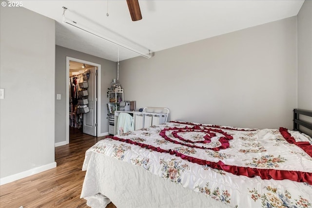 bedroom with hardwood / wood-style flooring, a spacious closet, ceiling fan, and a closet